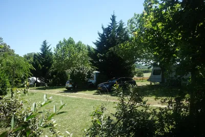 Camping La Magerie - schattige und von Bäumen geschützte Stellplätze mit daneben geparktem Auto
