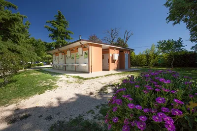 Camping La Perla del Lago - Das Sanitärgebäude von aussen mit Waschbecken im Freien