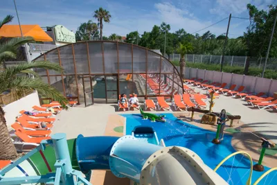 Camping la Sardane  -  Poolbereich vom Campingplatz mit Wasserrutsche, Indoor Pool, Kinderbecken und  Liegestühlen in der Sonne