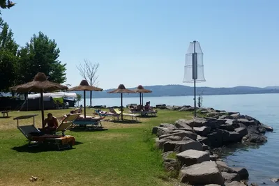 Camping La Spiaggia  -  Stellplatz und Liegewiese mit Sonnenschirmen und Liegestühlen am Trasimenischer See