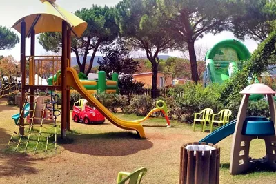 Camping Lacona Pineta - Kinderspielplatz mit Rutschen und Kletterburg, sowie Hüpfburgen im Hintergrund