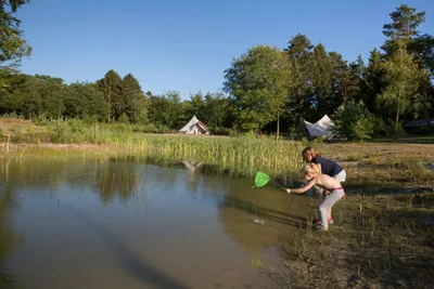 Landgoed Börkerheide - Kinder beim Fischen im Teich im Vordergrund, Zelte vom Campingplatz im Hintergrund