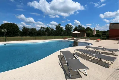 Le Village de Cottages - Freibad mit Liegestühlen auf dem Campingplatz