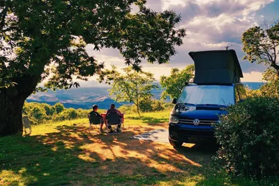 Camping Lucherino - Camper sitzen auf ihrem Standplatz im Schatten eines Baumes