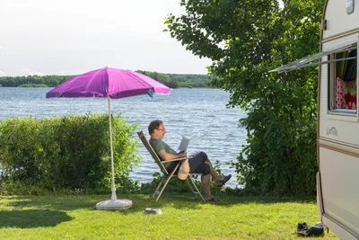 Naturcamping Spitzenort - Gast vor dem Wohnwagen im Schatten am Plöner See