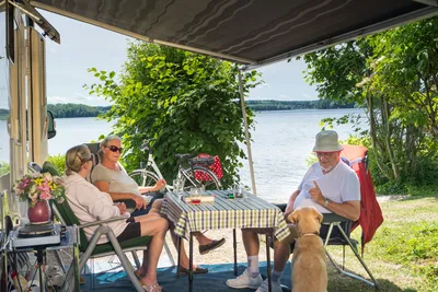 Naturcamping Spitzenort - Gäste vor dem Wohnwagen im Schatten am Plöner See auf dem Campingplatz