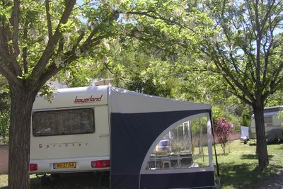 Camping Rose de Provence - Wohnwagen mit Vorzelt zwischen Bäumen