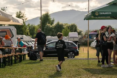 Schitterhof Camping - Camper sitzen zusammen auf Bierbänken auf der Standplatzwiese