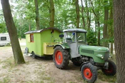 Schwielowsee-Camping - Zirkus Wohnwagen mit Traktor davor zwischen Bäumen
