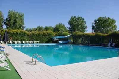 Camping Spinnaker - Pool vom Campingplatz mit Liegestühlen, Sonnenschirmen, Sitzmöglichkeiten und Wasserrutsche