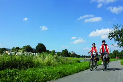 Weserbergland-Camping  - Camper fahren auf Fahrrädern entlang der Weser beim Campingplatz