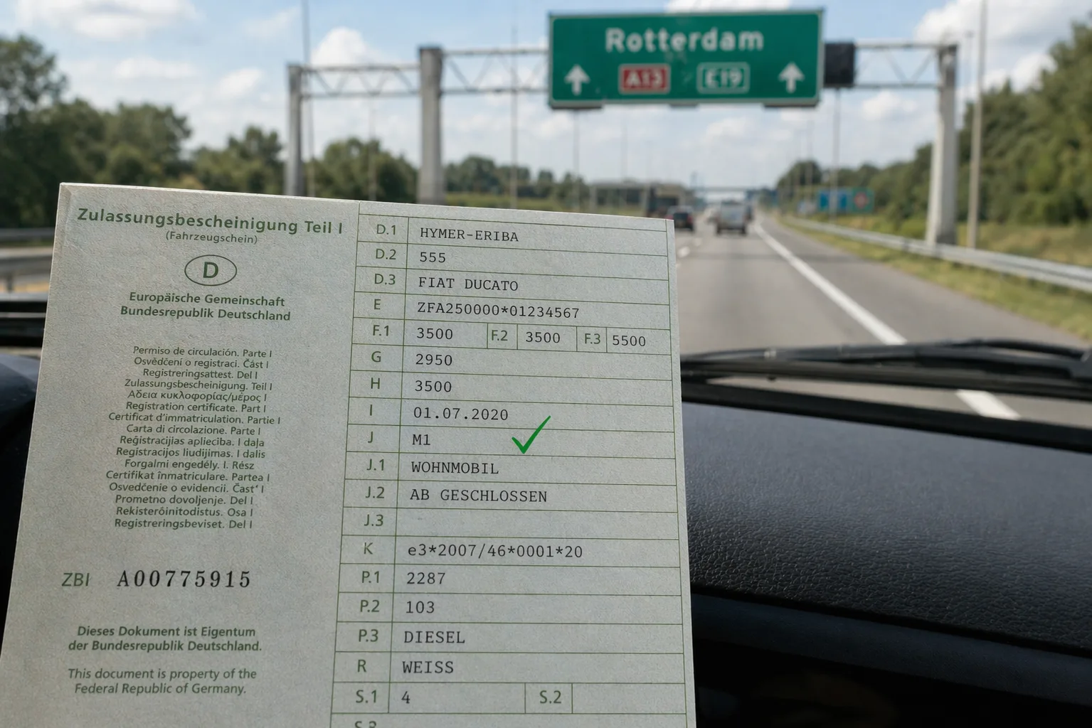 Deutscher Fahrzeugschein mit markiertem Feld J (Klasse M1) auf dem Armaturenbrett eines Wohnmobils vor niederländischer Autobahn